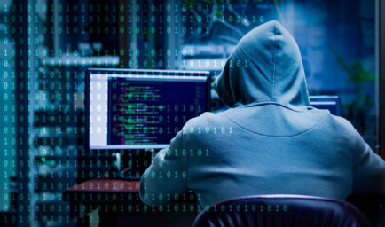 person in hoodie hacking a computer